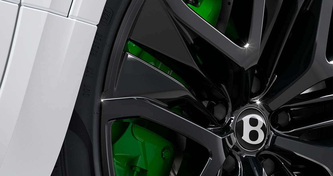 Close-up of gloss black Bentley wheel with green high-performance brake caliper on the 2026 Bentayga Speed, emphasizing style and stopping power.